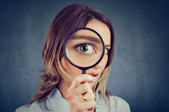 female looking through magnifying glass at the camera